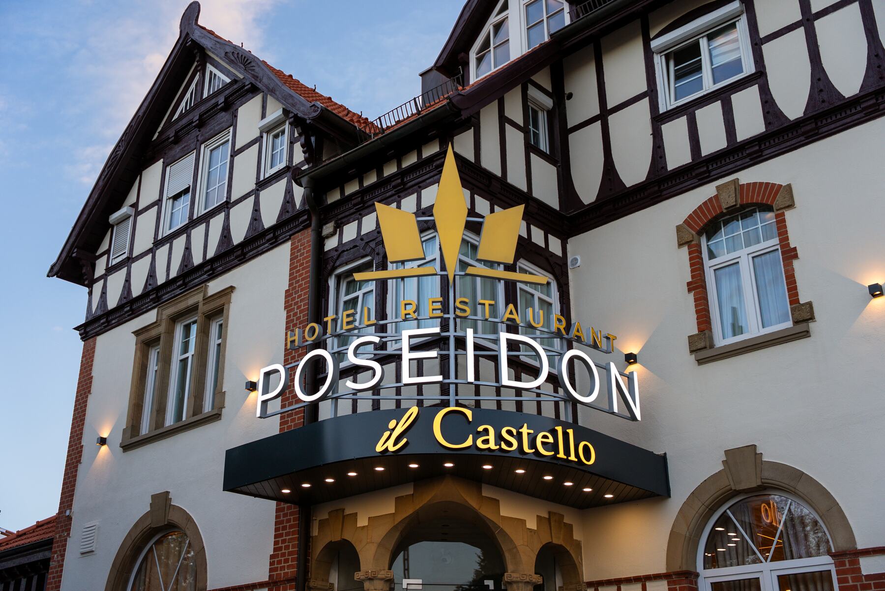 Hauseingang des Hotels Poseidon mit beleuchtetem Schriftzug und Fachwerkfassade