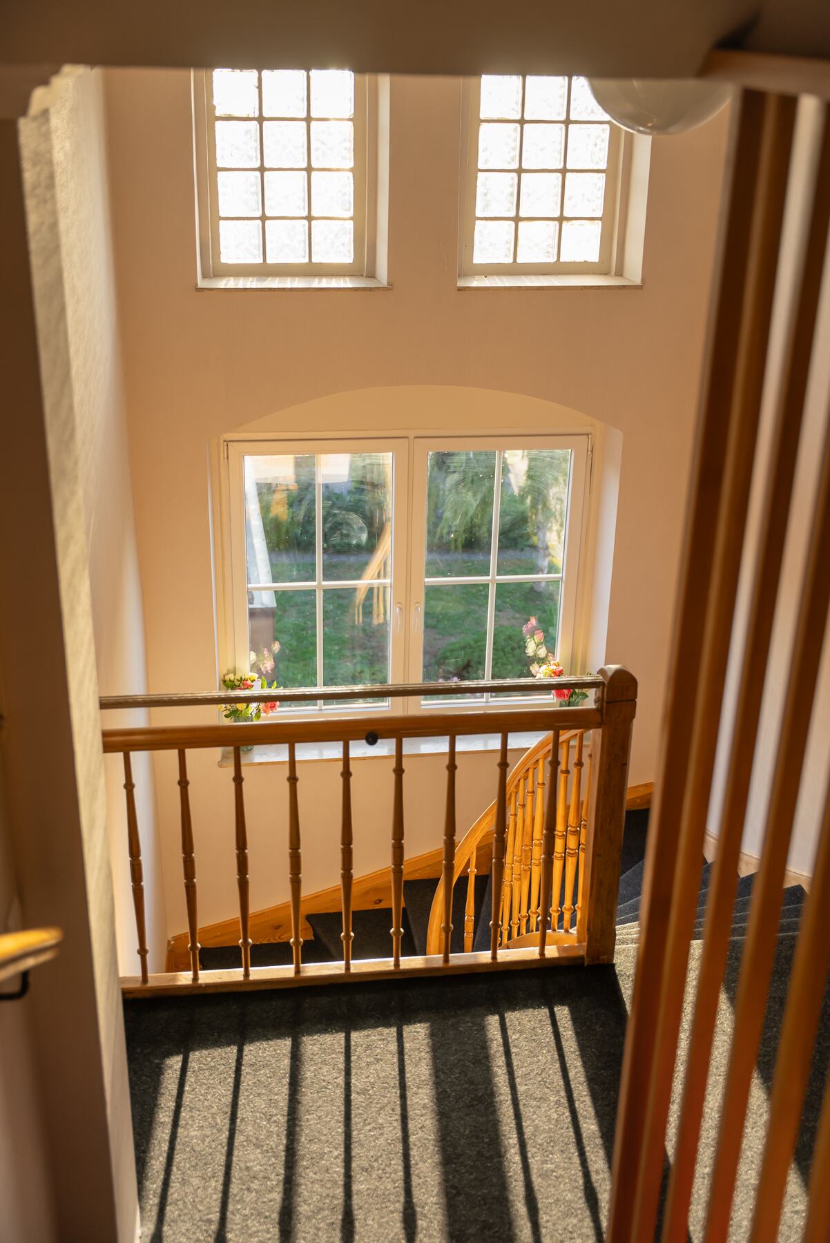 Treppenhaus mit Holzgeländer und Sprossenfenstern